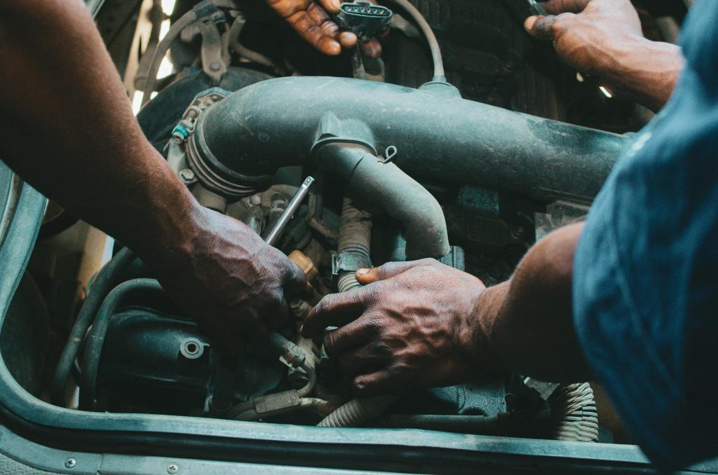 A professional mechanic working on a car engine inside a well-equipped auto repair garage at Carandtrucke